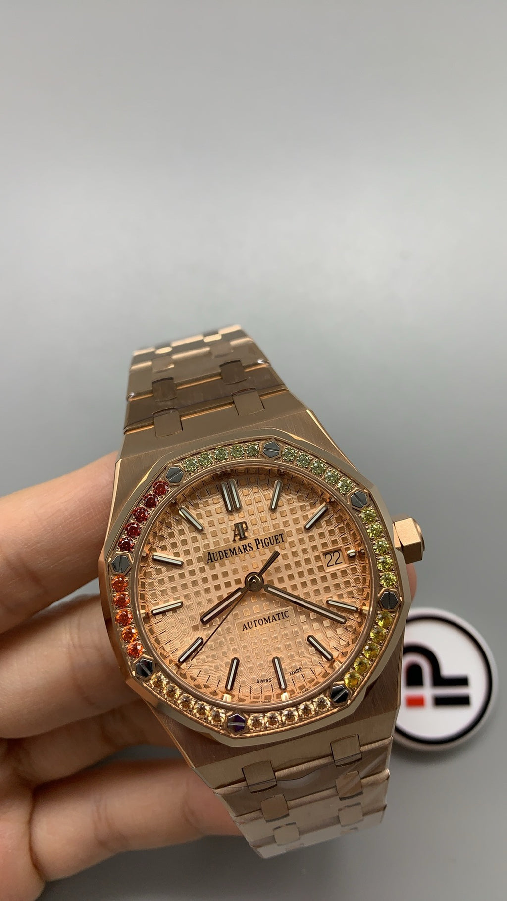 Audemars Piguet Royal Oak 15450 | 37MM | ตัวเรือนสแตนเลสสตีลเคลือบสีโรสโกลด์แบบ PVD | ขอบประดับอัญมณีสี彩รุ้ง (Rainbow Bezel) | หน้าปัดสีขาว | กลไกอัตโนมัติ Cal.3120