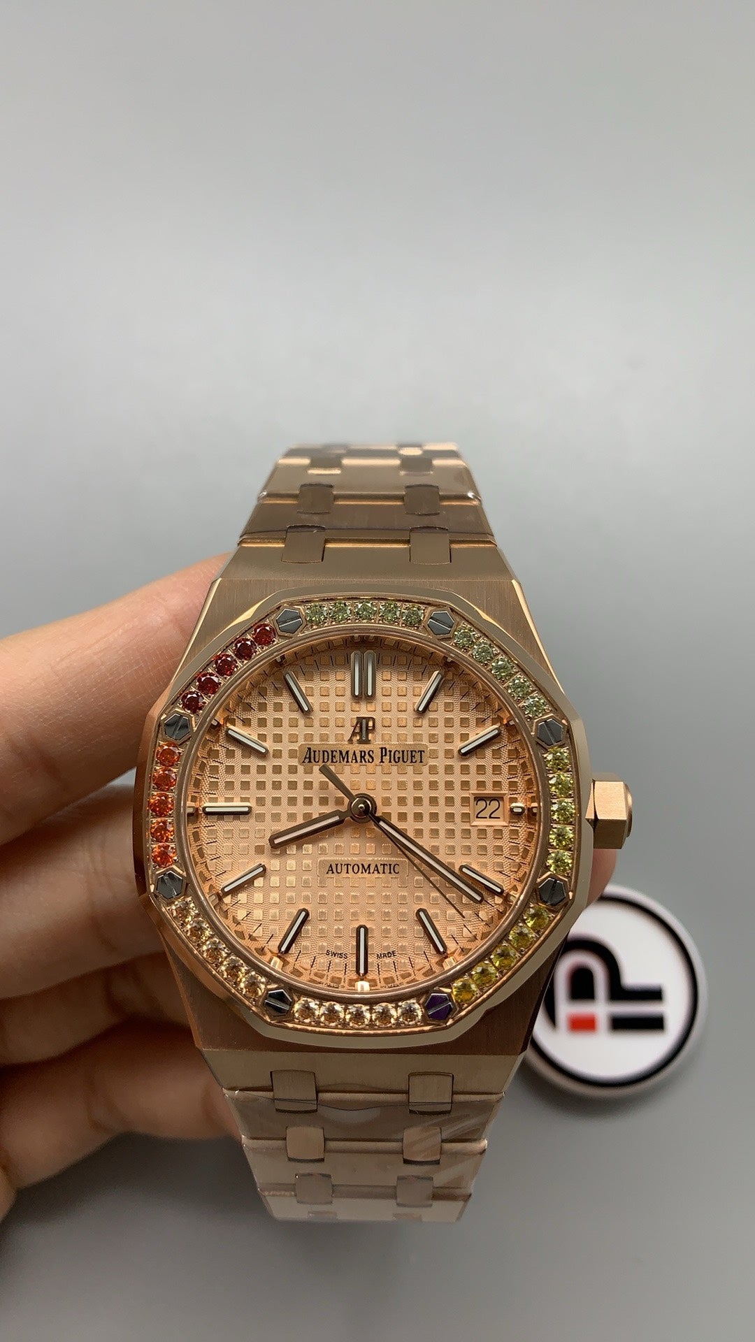 Audemars Piguet Royal Oak 15450 | 37MM | ตัวเรือนสแตนเลสสตีลเคลือบสีโรสโกลด์แบบ PVD | ขอบประดับอัญมณีสี彩รุ้ง (Rainbow Bezel) | หน้าปัดสีขาว | กลไกอัตโนมัติ Cal.3120
